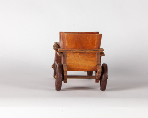 Rear of wooden depiction of an early car. Several shades of wood.