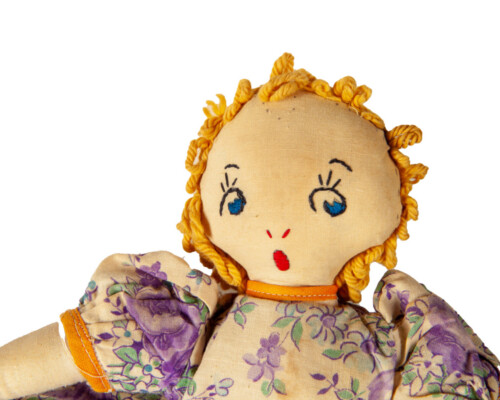 Face of blonde side of reversible doll. Purple and pink floral pattern.