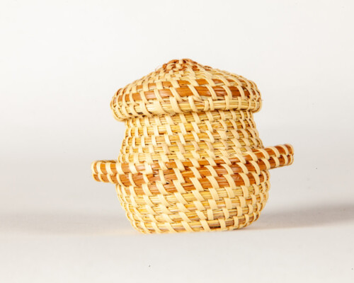 Close up of small woven sweetgrass basket with matching lid.