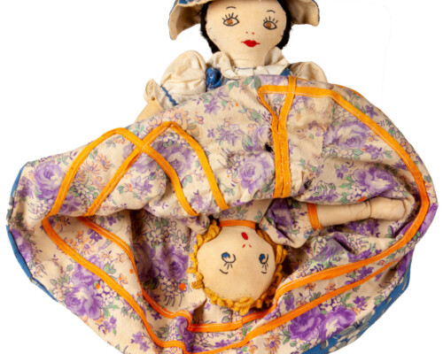 Reversible doll with both faces showing, pink and purple floral dress pattern.