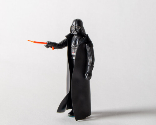 Front view of Darth Vader action figure pointing lightsaber forward.