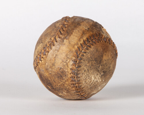 Close up of aged baseball. Surface is weathered and brown.