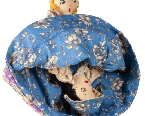 Reversible doll with both faces showing, blue and pink floral dress pattern.