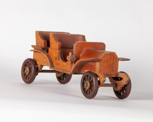 Wooden depiction of early automobile. Multiple colors of wood.