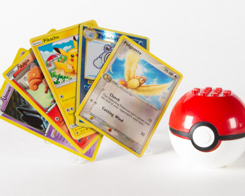 White, black, and red Mega Bloks pokeball with 5 Pokémon cards next to it.