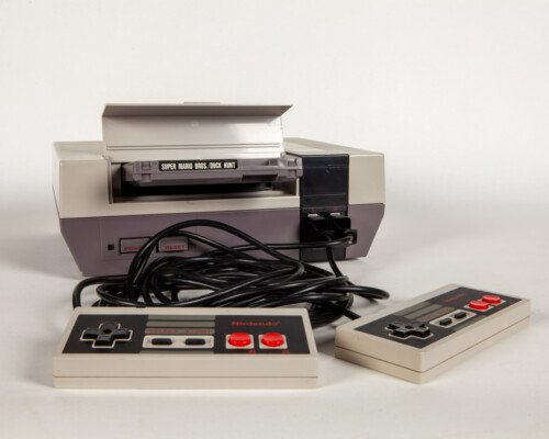 Nintendo Entertainment System with two controllers and a cartridge in the tray.